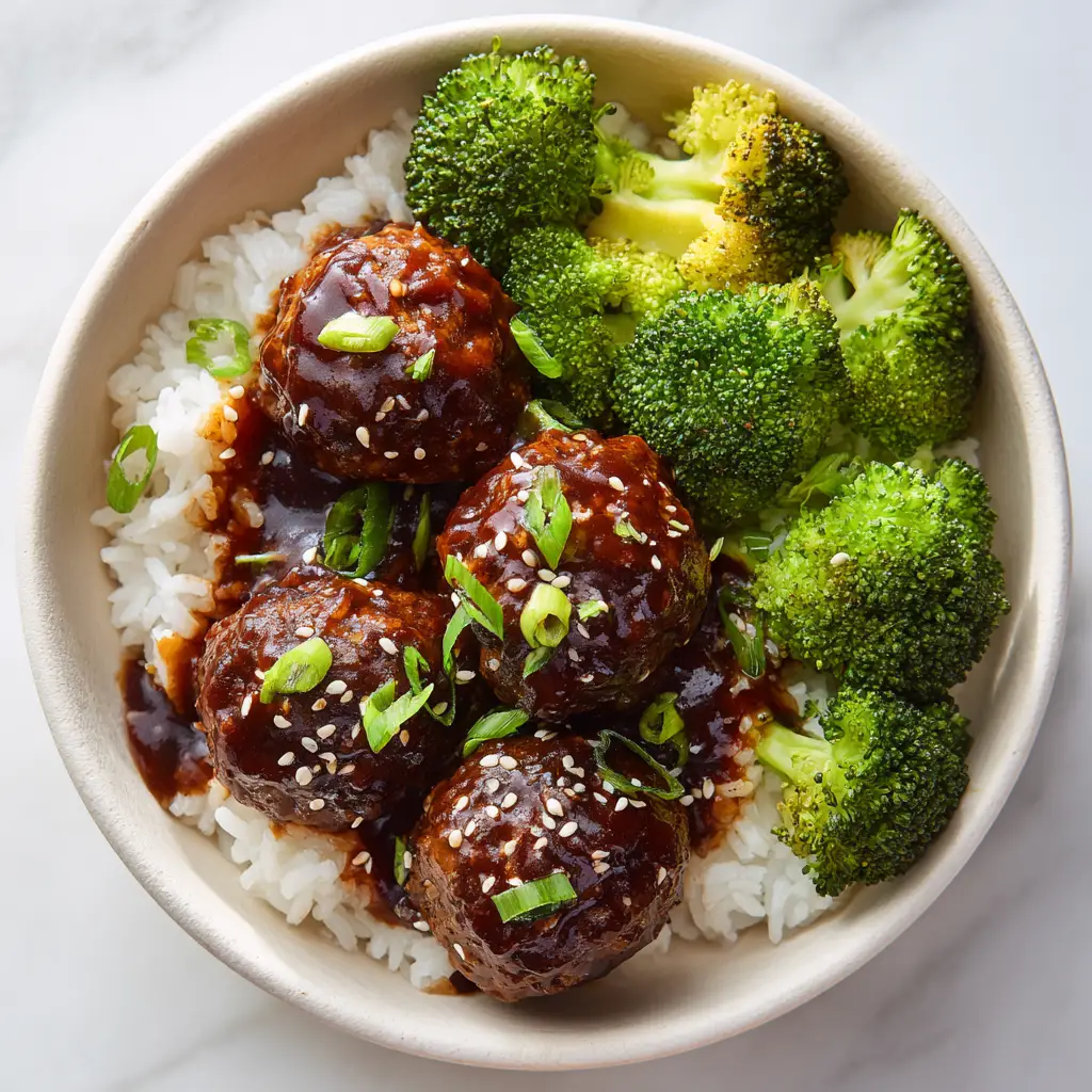 A side-angle shot of the Mongolian Meatballs, highlighting the texture of the tender ground beef meatballs and the crisp steamed broccoli florets.