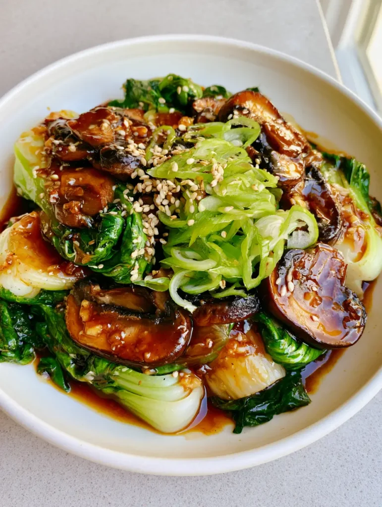 A top-down view of the Bok Choy and Mushroom Stir Fry showing the translucent garlic soy glaze and sesame seed garnish.