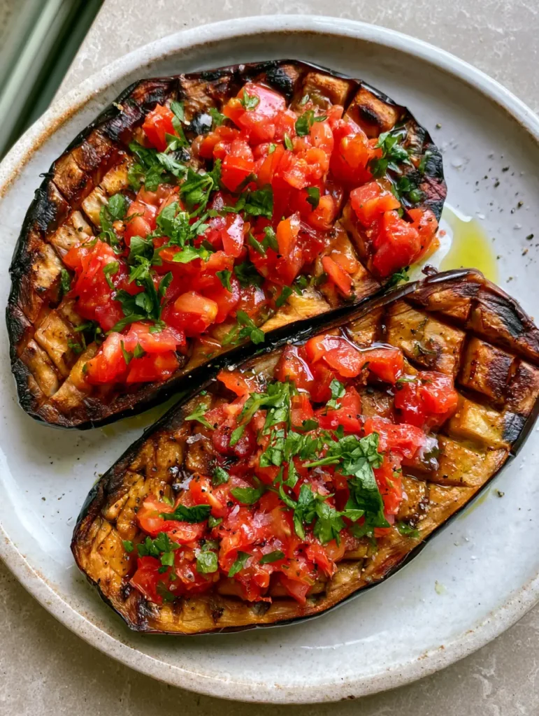 Mediterranean Roasted Eggplant with Garlic and Fresh Tomato Topping 1 Close-up of charred edges and golden-brown flesh of Mediterranean Roasted Eggplant.