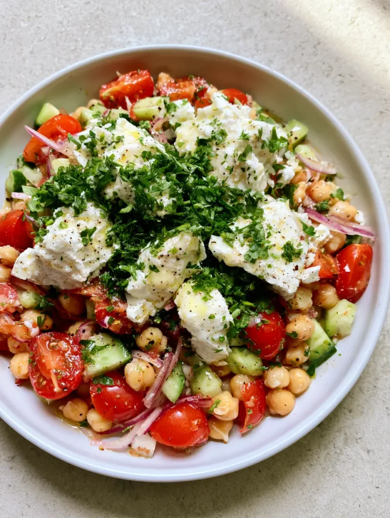 High-Protein Chickpea Salad with Lemon Vinaigrette and Feta 2 Close-up of a vibrant High-Protein Chickpea Salad showing plump rinsed chickpeas, crisp diced cucumbers, and bright halved cherry tomatoes coated in a translucent lemon oil dressing.