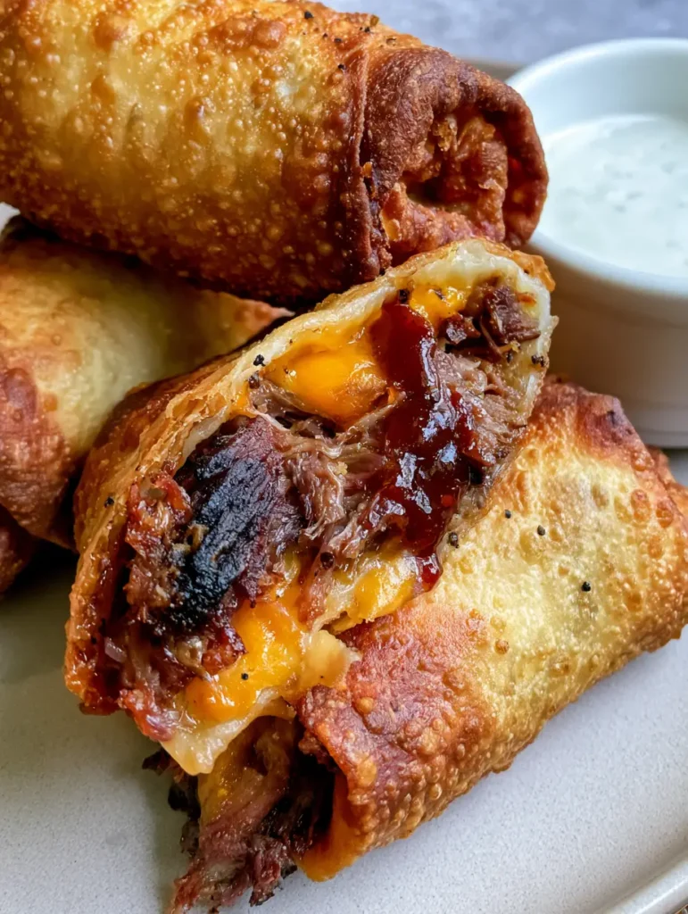 BBQ Egg Rolls with Smoked Brisket and Sharp Cheddar 2 A smartphone photo of stacked BBQ Egg Rolls showing the crispy deep-fried texture and micro-bubbles. (BBQ Egg Rolls)