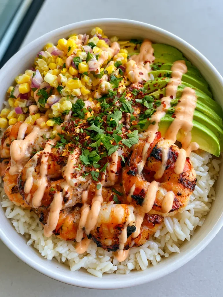 Close-up of charred grilled shrimp and fresh corn salsa over a bed of fluffy white rice.