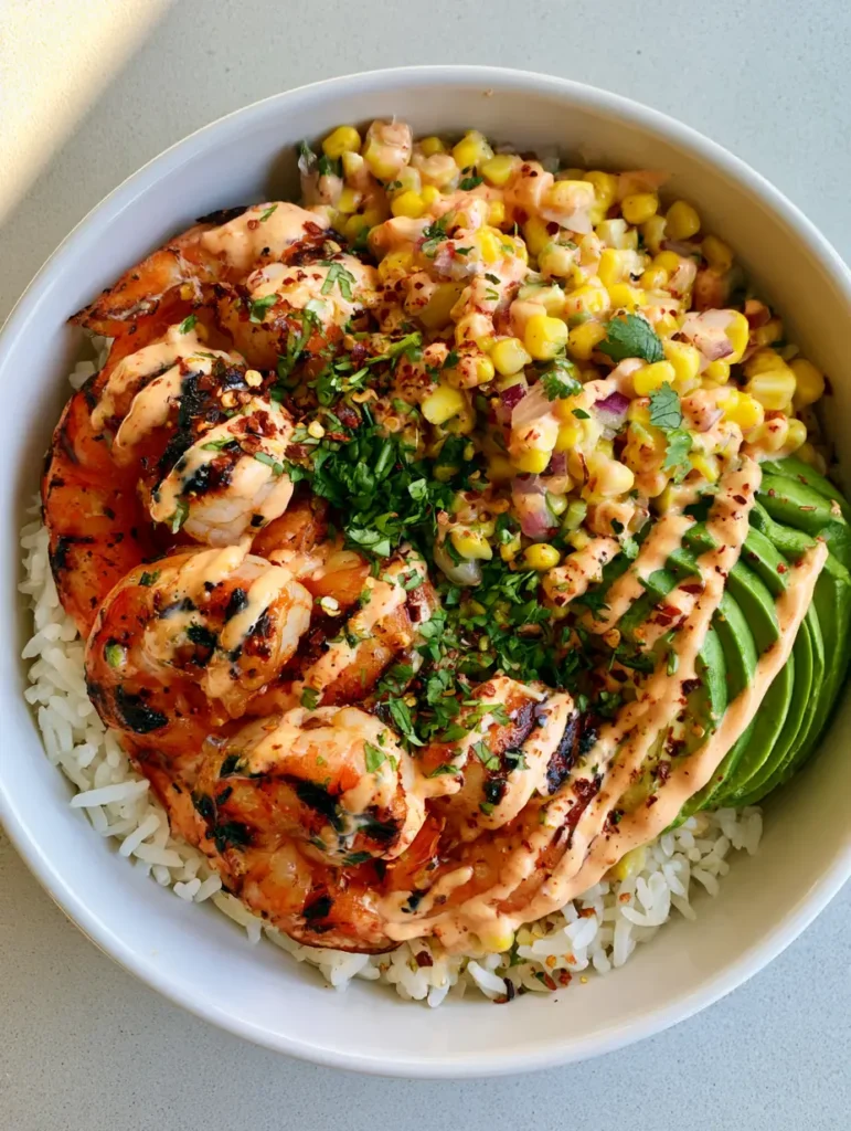 Complete Grilled Shrimp Bowl featuring fanned avocado and a creamy pale orange chipotle sauce drizzle.