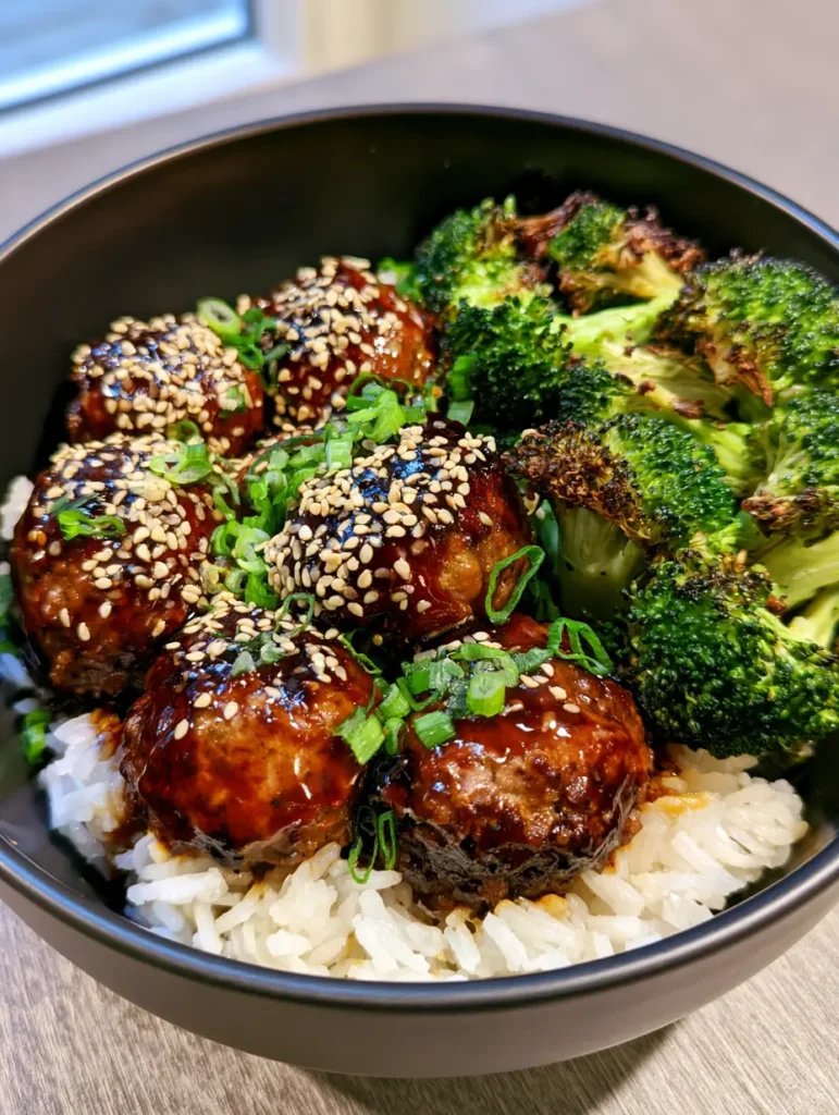 A bowl of Mongolian Meatballs showing the contrast between the dark sauce and vibrant green broccoli with charred tips.